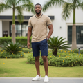 Nigerian male model wearing men's khaki polo shirt with navy tipping, garden setting