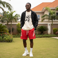 Nigerian male model wearing crimson red angled triple-stripe sweat shorts — full body streetwear shot