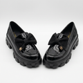 Complete pair of black glossy bow-detail chunky loafers on white
