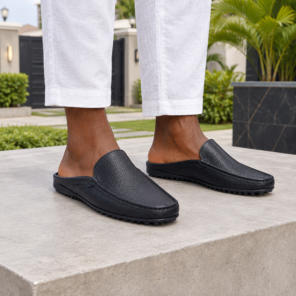 Man wearing black pebble grain backless mule slippers with white linen trousers