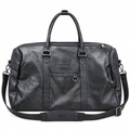 Black travel duffle bag with handles and shoulder strap on white