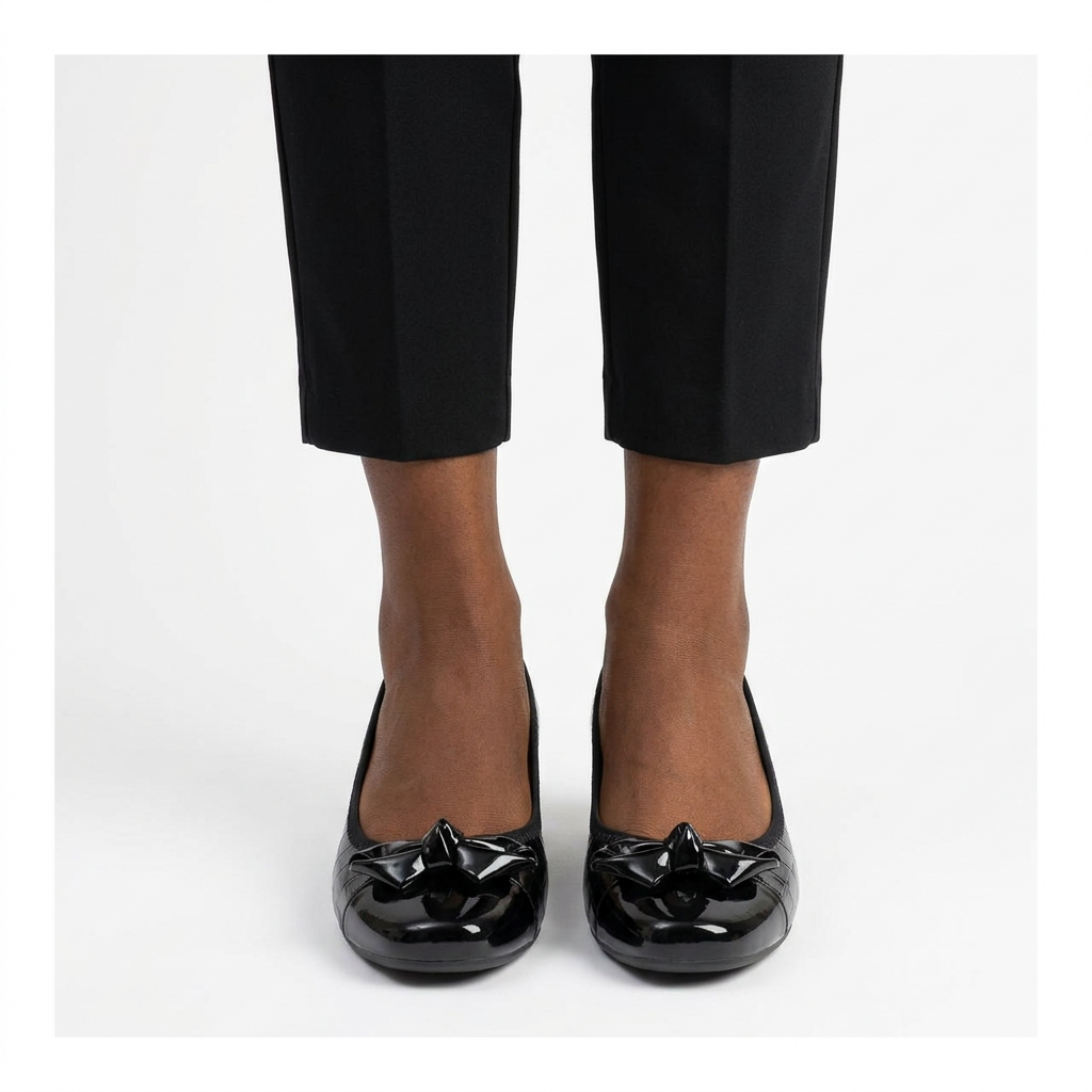 Adult woman wearing black sculpted-bow wedge shoes with feet together