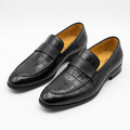 Pair of black croc-embossed strap loafers with tan lining on white