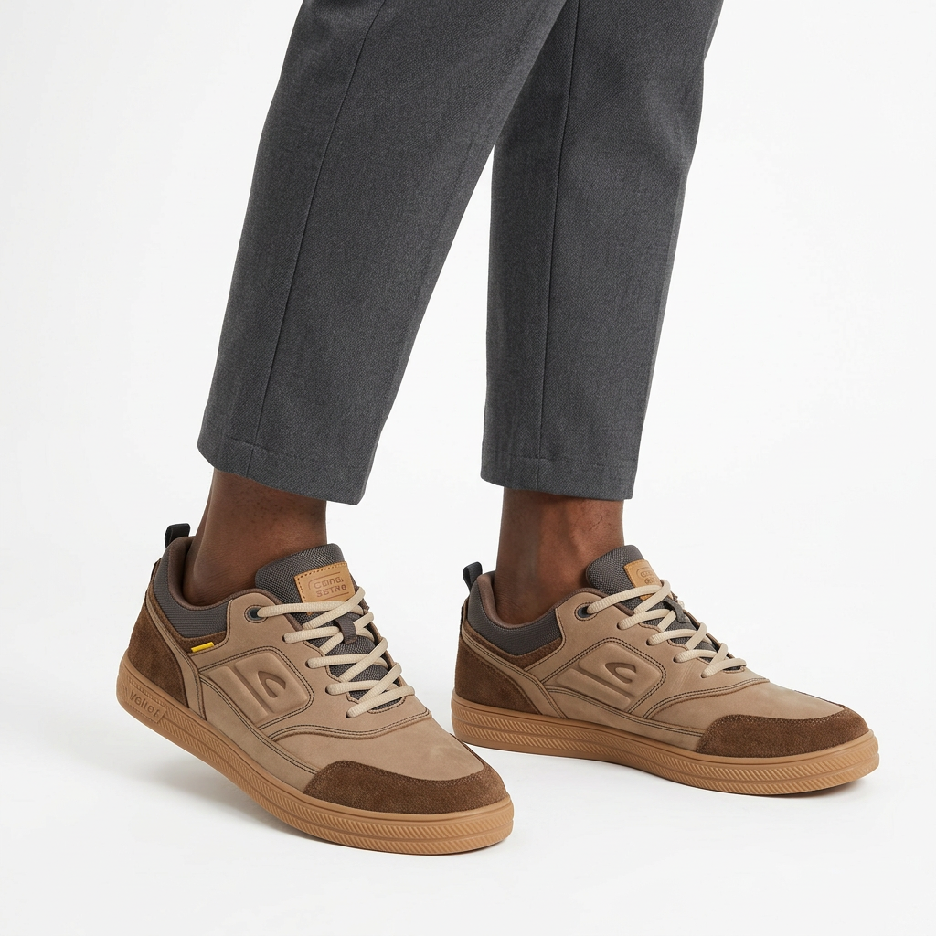 Men's taupe and brown gum-sole sneakers worn ankle-down on a white studio background