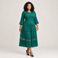 Black Nigerian model wearing an emerald tiered pleated gown with bell sleeves