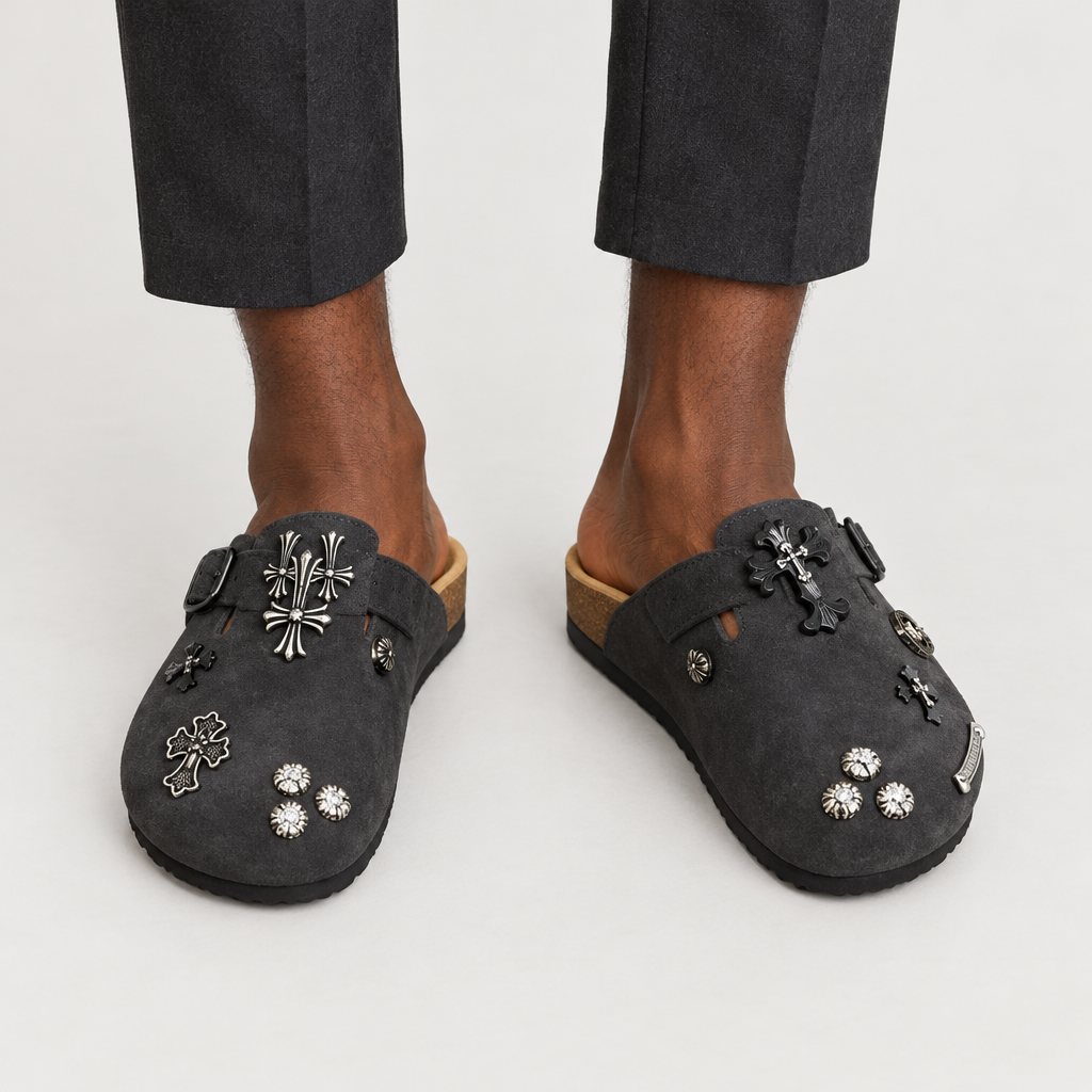Both feet wearing charcoal cross-charm clogs on plain background