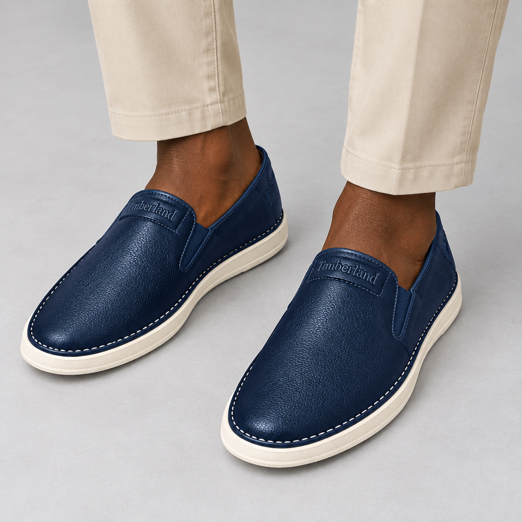 Navy slip-on shoes worn with beige trousers