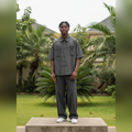 Nigerian male model full body wearing men's charcoal pinstripe boxy short-sleeve shirt