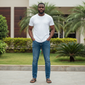 Adult Nigerian male model wearing medium blue wash straight denim jeans in garden setting