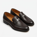 Pair of deep brown H-detail apron-toe loafers on a white background
