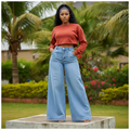 Nigerian female model wearing women's light blue high-waist extra wide-leg palazzo denim jeans, garden setting