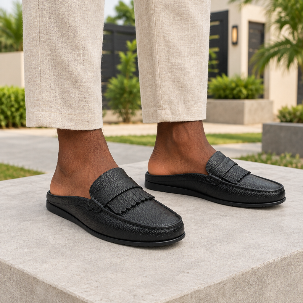 Man wearing black fringe kiltie backless mule slippers with beige linen trousers