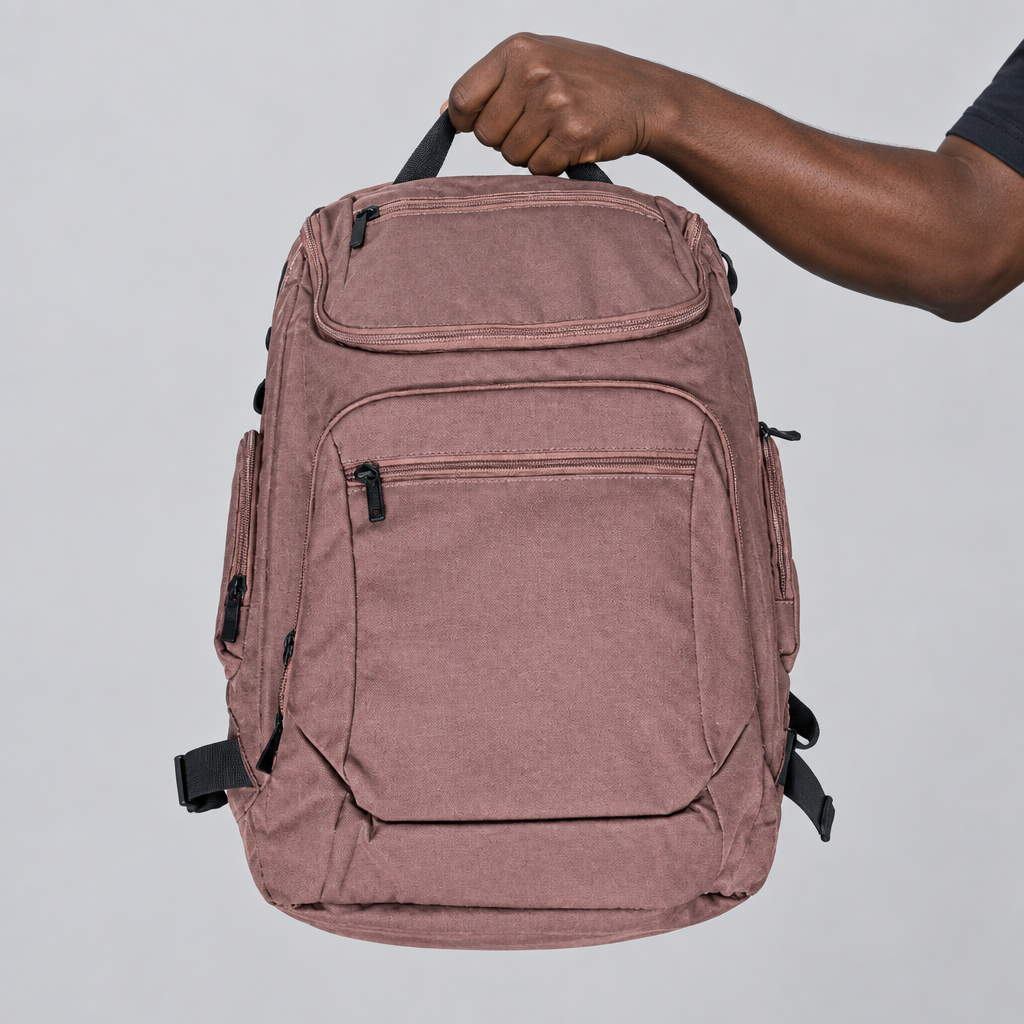 Hand holding the top handle of a mauve multi-pocket travel backpack