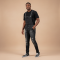 Man wearing washed black distressed denim bib overalls over a black t-shirt