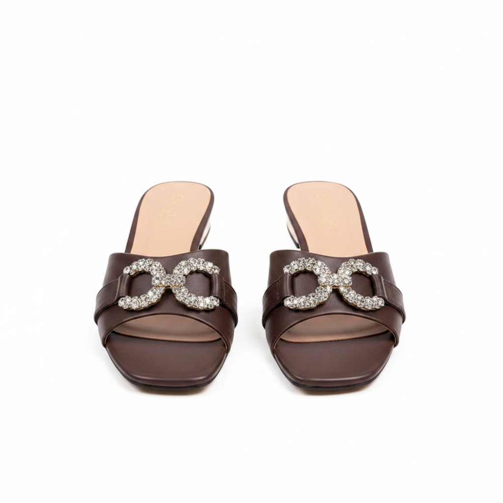 Pair of dark chocolate brown square-toe low block heel mule sandals with crystal buckle on white background