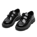 Pair of glossy black double-strap moc-toe children’s shoes with contrast welt detailing on white