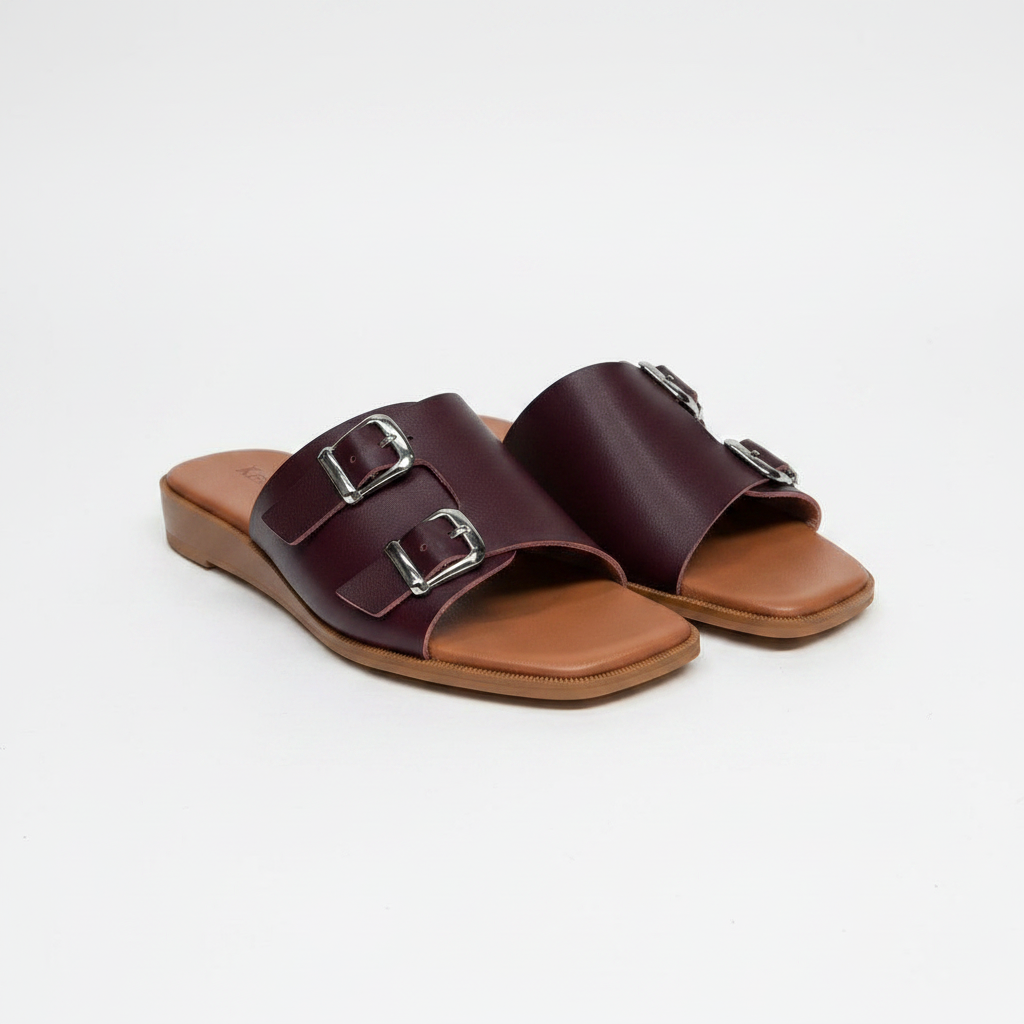 Pair of burgundy leather double buckle flat slide slippers on white background