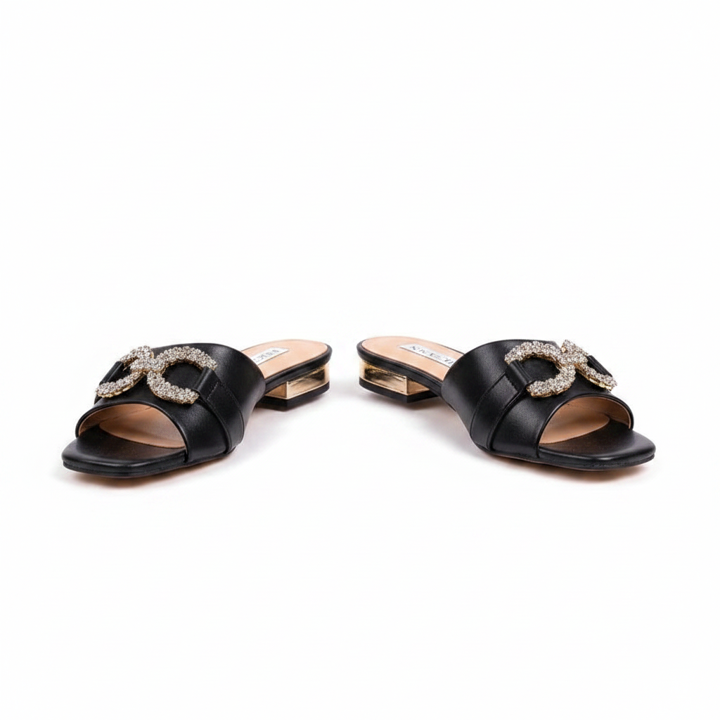 Pair of black square-toe low block heel mule sandals with crystal buckle on white background