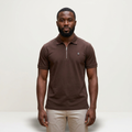Male model wearing a chocolate brown zip-neck polo shirt against a plain off-white background