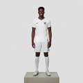 Nigerian male model full body wearing white home football jersey with white shorts on concrete plinth