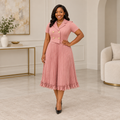 Adult Black woman wearing a dusty pink lapel pleated dress