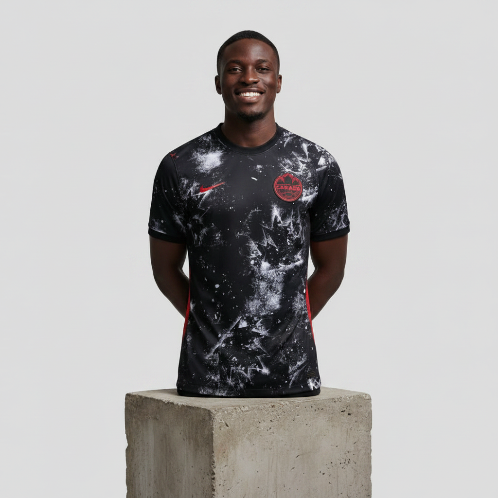 Nigerian male model wearing black galaxy splatter graphic football jersey on concrete plinth