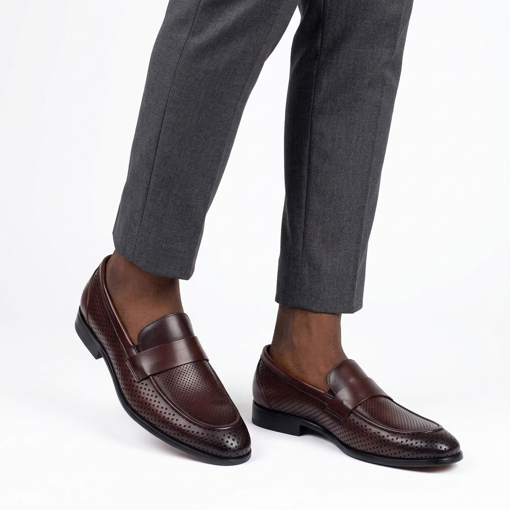 Dark brown perforated loafers worn on both feet with grey trousers