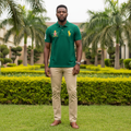 Nigerian male model wearing men's forest green big pony polo shirt with Union Jack crest badge, garden setting