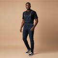 Man wearing dark indigo denim bib overalls over a black t-shirt