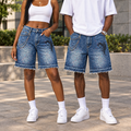 Young Nigerian woman and man both wearing blue paint-splatter denim shorts with chain and wing embroidery