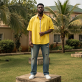 Nigerian male model wearing yellow oversized short-sleeve button-down shirt – full body lifestyle shot