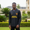 Black long-sleeve retro football jersey with yellow sponsor and diamond pattern — Nigerian male model front view