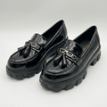 Matching black glossy twin-tassel chunky loafers standing together