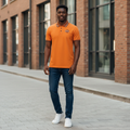 Young Nigerian male model wearing orange polo with navy striped collar and NG badge