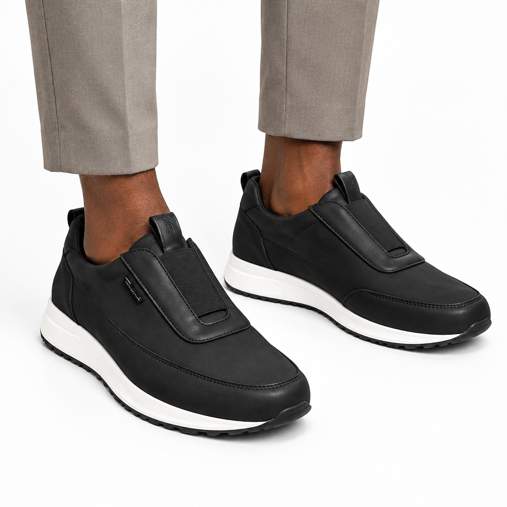 Both black panelled slip-on shoes worn ankle-down on white
