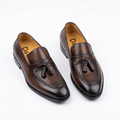 Pair of burnished dark brown tassel loafers on white