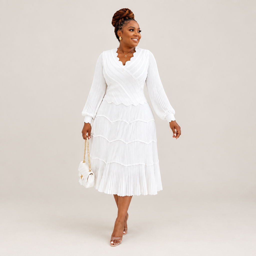 Black Nigerian model wearing a white tiered pleated gown with bell sleeves and a scalloped neckline