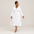 Black Nigerian model wearing a white tiered pleated gown with bell sleeves and a scalloped neckline