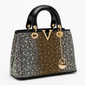 Black handbag with gold-tone centre and silver-tone studded outer sections on white
