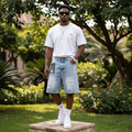 Nigerian male model wearing men's light blue washed distressed denim shorts streetwear style