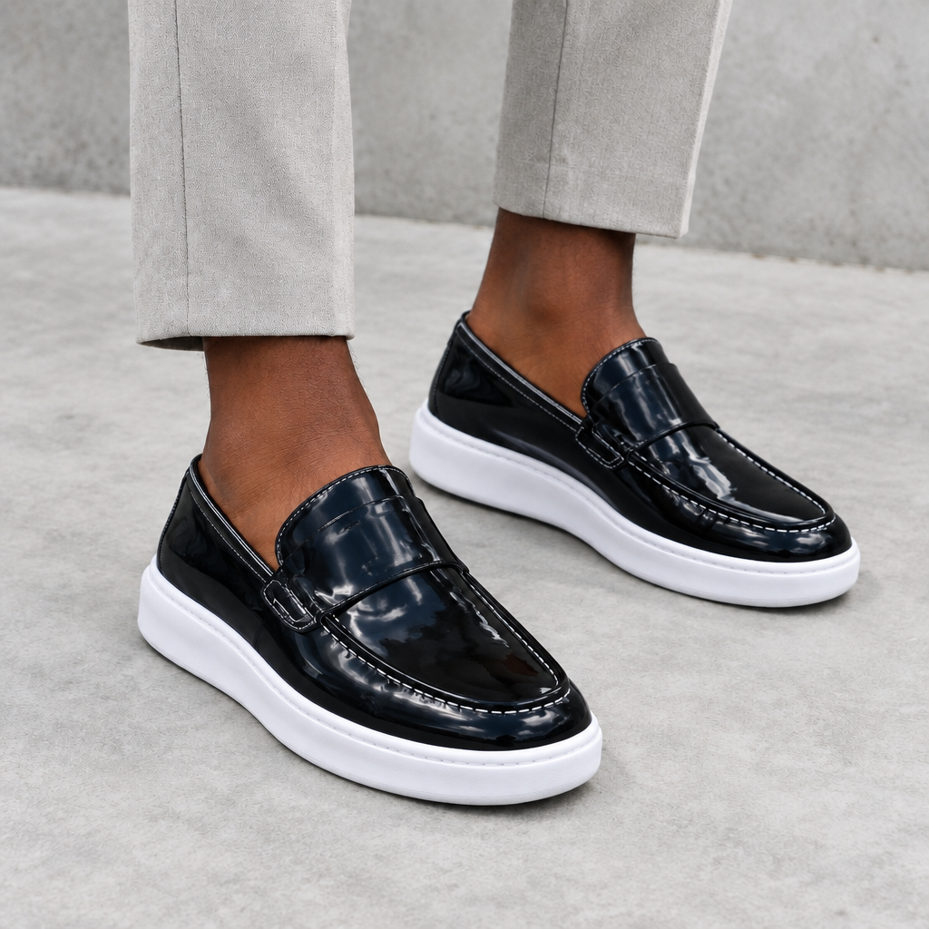Glossy black loafers with a wide vamp strap and white sole, worn on both feet