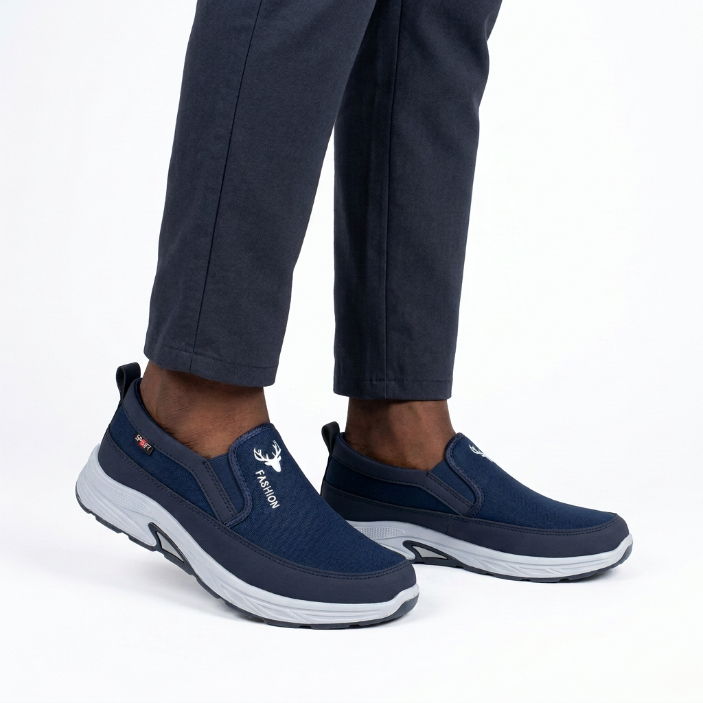 Navy slip-on shoes worn on both feet by a Black male model on white