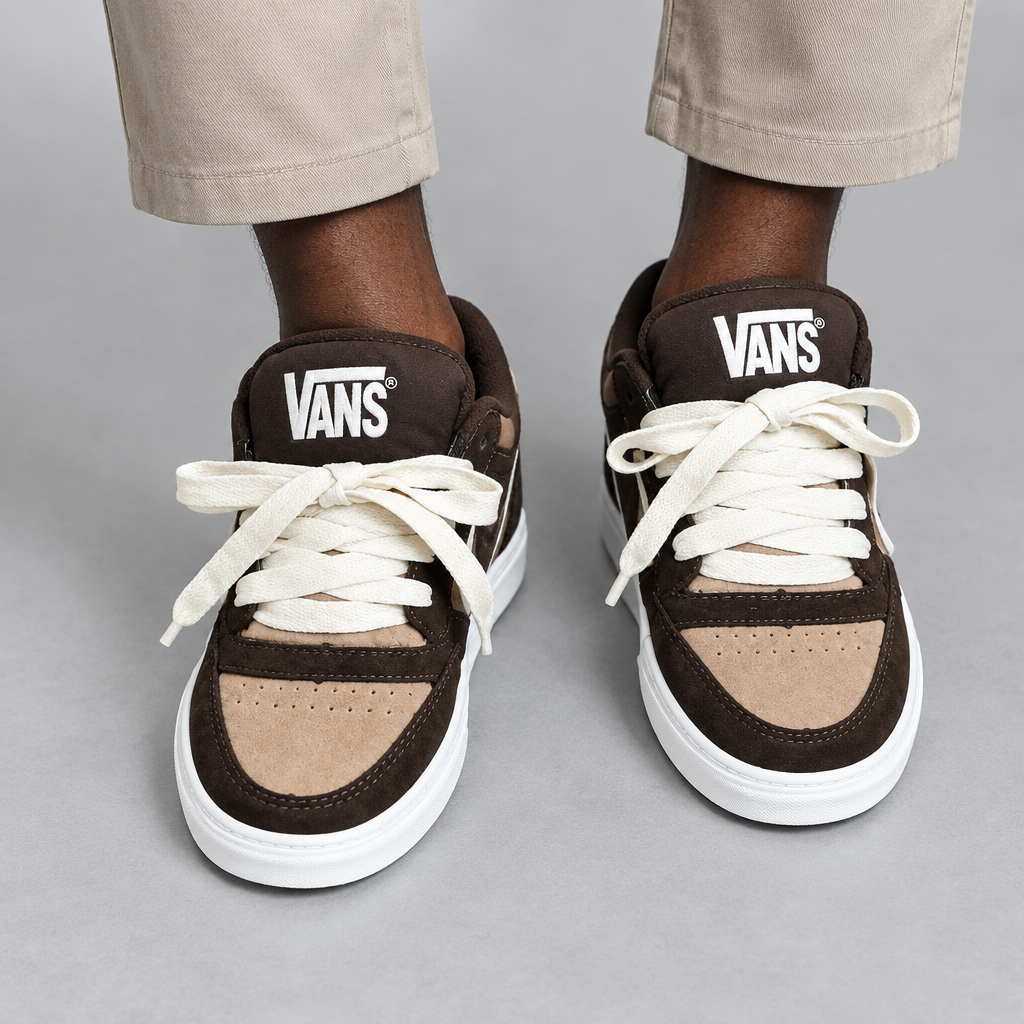 Lower-leg view of Nigerian man wearing brown-and-tan low-top sneakers, both shoes visible