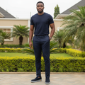 Nigerian male model wearing navy blue suede slip-on sneakers with grey sole in garden setting