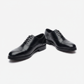 Polished black leather cap-toe derby shoes, centred on a plain off-white background