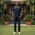 Nigerian male model wearing men's navy polo shirt with cream contrast collar, garden setting