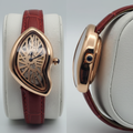 Asymmetric rose gold skeleton dial watch with red strap front and side view