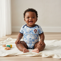 Nigerian baby wearing white & blue graphic print football romper bodysuit lifestyle shot