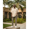 Nigerian male model wearing grid-textured short-sleeve utility shirt in warm ivory — full body street style