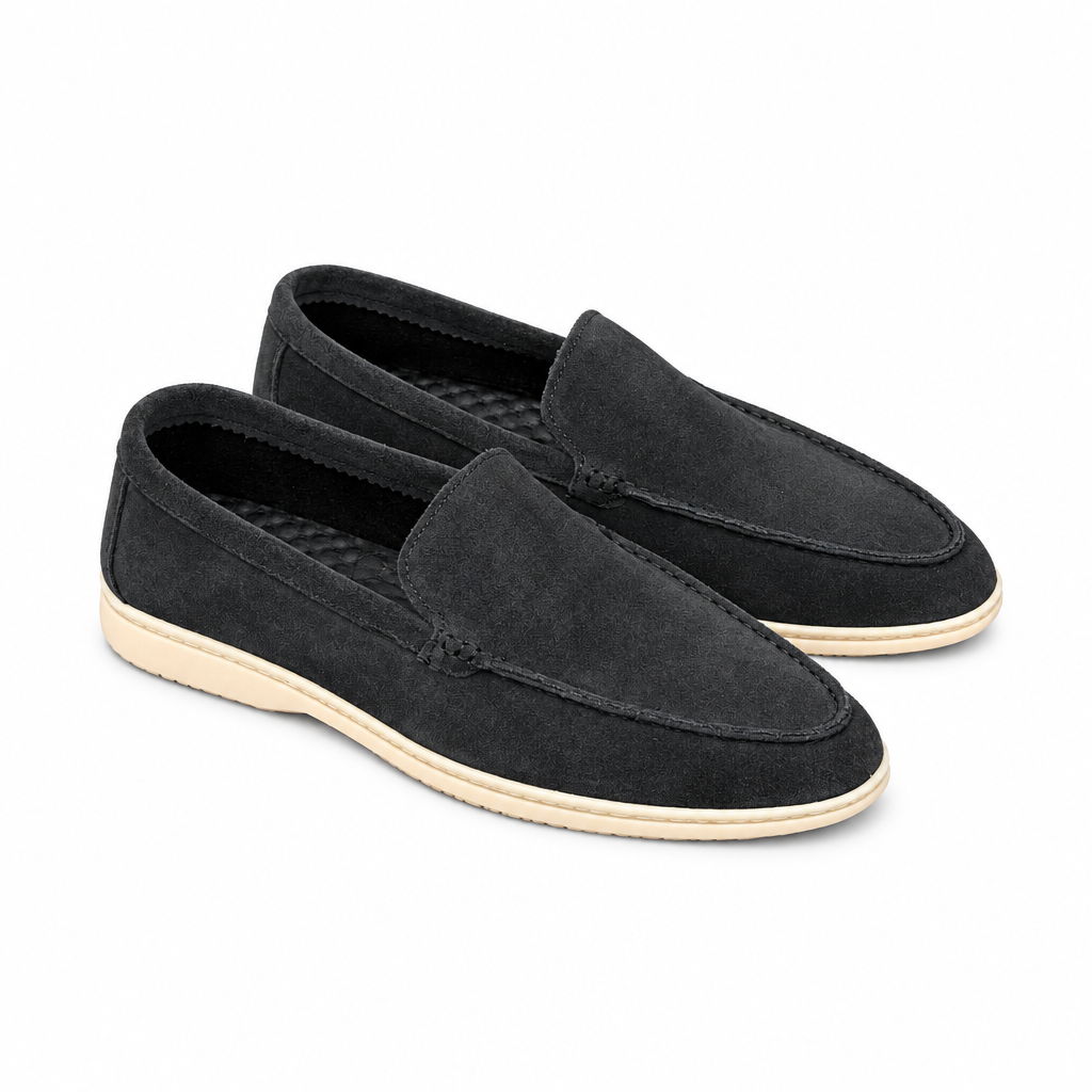 A pair of charcoal-black suede moc-stitch loafers with cream soles on white